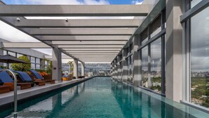 A modern indoor swimming pool with lounge chairs and large windows offering city views. - HW Rebou As2636-210 (São Paulo)