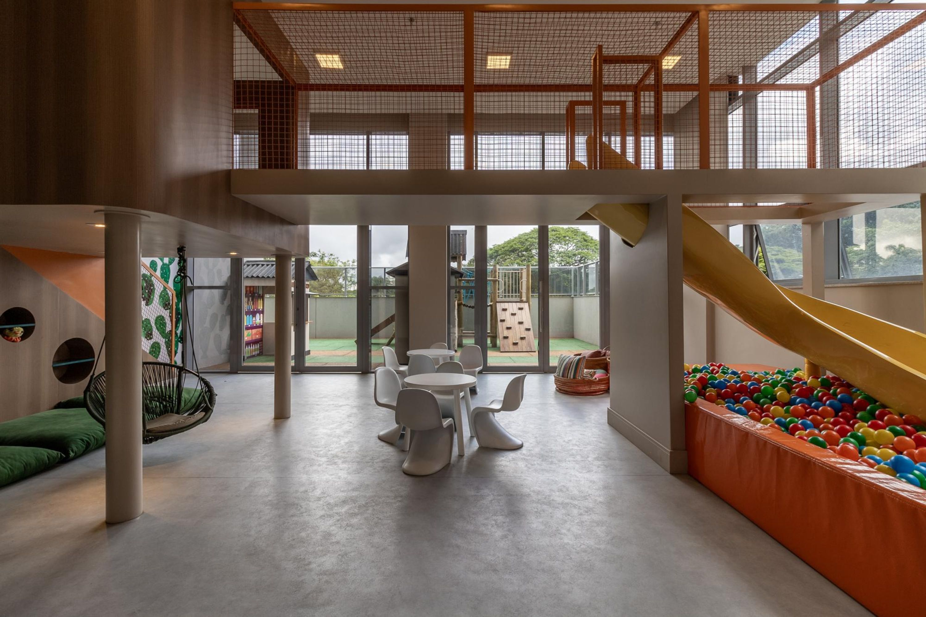 Uma área de recreação interna ampla, com escorregador, piscina de bolinhas e espaço para sentar.