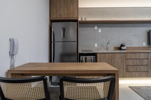 Une cuisine moderne équipée d’un réfrigérateur encastré, d’une machine à café et d’un four à micro-ondes. On y trouve une table à manger en bois avec deux chaises.
