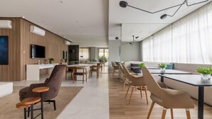 Ein modernes Wohnzimmer mit einer Couch, Sesseln und einem Couchtisch. Es gibt einen Essbereich mit Tisch und Stühlen.