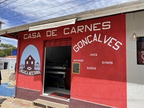 A red building with a sign reading "Casa de Carnes Goncalves" and a logo for "Lingua Artesanal". - Casagon Alves in Gon Alves (Gonçalves)