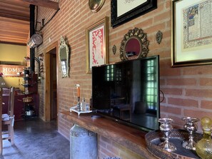 A cozy living room with a brick wall, a television, and various decorative items including framed pictures and a mirror. - Casagon Alves in Gon Alves (Gonçalves)