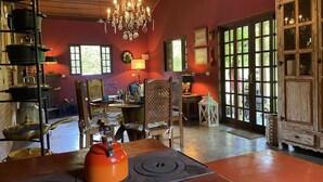 A dining area with a wooden table, chairs, a chandelier, and a view through a large window. - Casagon Alves in Gon Alves (Gonçalves)