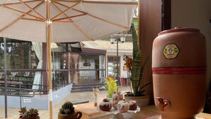 A terrace with a wooden table, a terracotta pot, potted plants, and a large umbrella. - Casagon Alves in Gon Alves (Gonçalves)