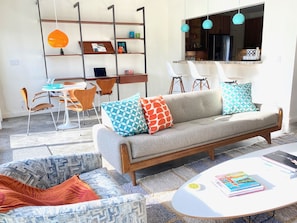 Un salon moderne comprenant un canapé, deux fauteuils, une table basse et un coin repas avec des chaises et une table.