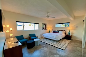 Une chambre à coucher avec un lit, un bureau, une chaise, un canapé et une fenêtre.