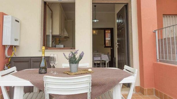 Un espacio de comedor al aire libre con una mesa dispuesta para dos, una botella de champán y una planta en maceta.