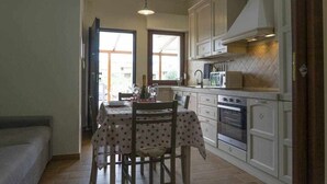Una cocina compacta con una mesa, sillas y electrodomésticos básicos.