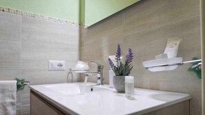 Un baño moderno con un lavabo blanco, un espejo y una planta de lavanda en maceta.