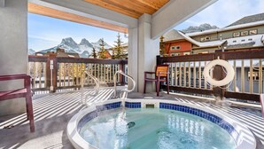 Un jacuzzi con vista a la montaña, terraza de madera y un flotador.