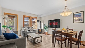 Una sala de estar con chimenea, comedor y televisor montado en la pared.
