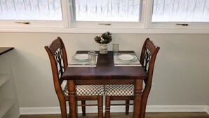 A dining table with chairs, a vase with a plant, and glassware. - Renovated Suite with 1 queen bed and a Twin. Kitchen & bath for your privacy. (Goldsboro)