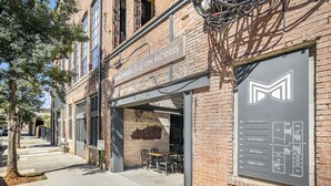 A brick building with a storefront labeled "Mercantile on Morris" and a directory listing various rooms and amenities. - Iconic Morris Ave condo retreat sleeps 6 +rooftop (Birmingham)