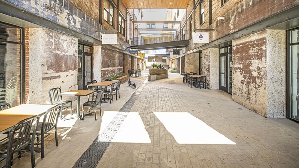 An indoor courtyard with brick walls, wooden ceiling, and tables and chairs arranged for dining. - Iconic Morris Ave condo retreat sleeps 6 +rooftop (Birmingham)