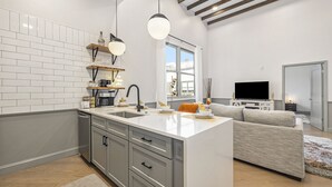 A modern kitchen with a central island, grey cabinetry, and a built-in oven. - Iconic Morris Ave condo retreat sleeps 6 +rooftop (Birmingham)