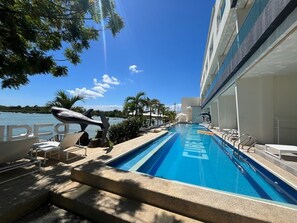 A swimming pool with lounge chairs and a view of the sea. - Cube9 Resort and Spa (Lapu-Lapu)