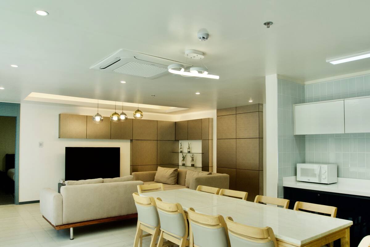 A modern kitchen with a dining area, built-in cabinets, and a flat-screen TV.