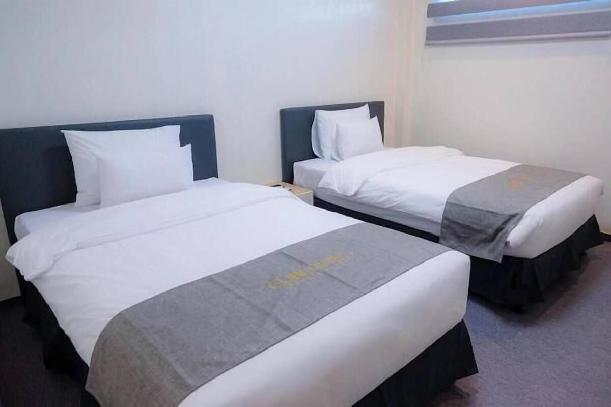 Two single beds with white linens and dark headboards in a hotel room.