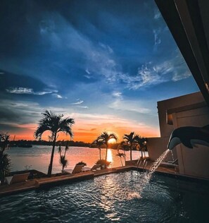 A poolside view with a sunset over water, palm trees, and lounge chairs. - Cube9 Resort and Spa (Lapu-Lapu)
