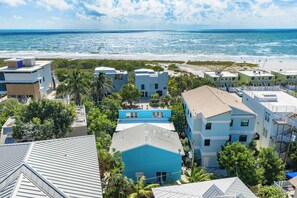 A coastal residential area with modern buildings, a beach, and clear skies.