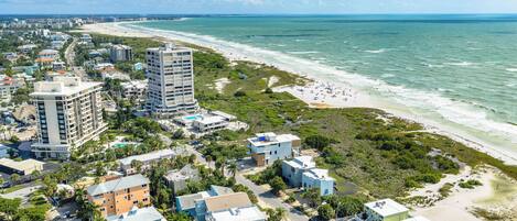 A coastal cityscape with beachfront hotels, dense urban buildings, and a sandy beach.