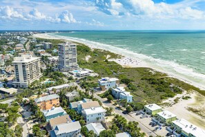 A coastal cityscape with beachfront hotels, dense urban buildings, and a sandy beach.