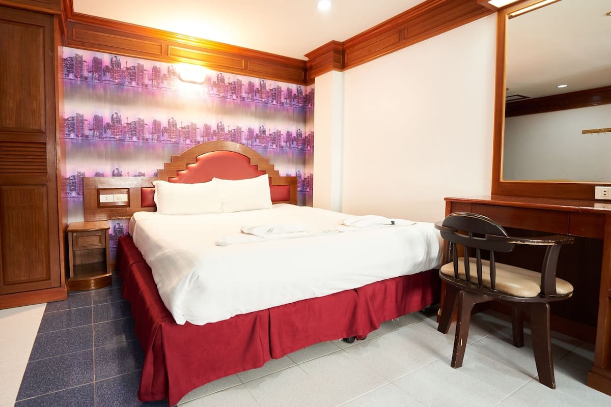 Una habitación de hotel con una cama, un escritorio, una silla y un armario.