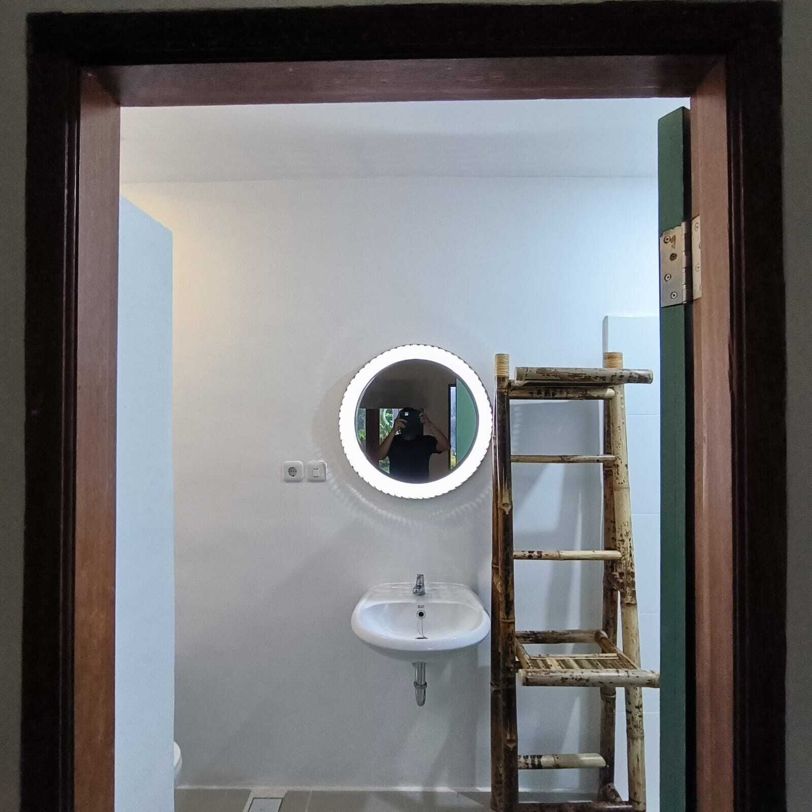 A bathroom with a white sink, a mirror, and a wooden ladder leaning against the wall.