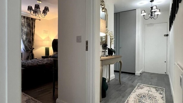 A hallway with a bed, bedside table, lamp, and a mirror. - Remarkable 2-Bed Apartment in Castlebar (Castlebar)