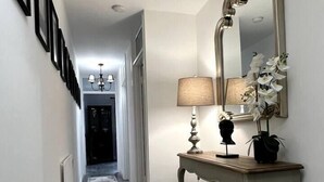 A hallway with a patterned rug, a console table with a lamp, a mirror, and framed pictures on the wall. - Remarkable 2-Bed Apartment in Castlebar (Castlebar)