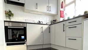 A modern kitchen with white cabinets, black countertops, and a built-in oven. - Remarkable 2-Bed Apartment in Castlebar (Castlebar)