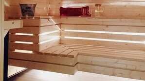A sauna room with wooden benches and a bench with a red towel.