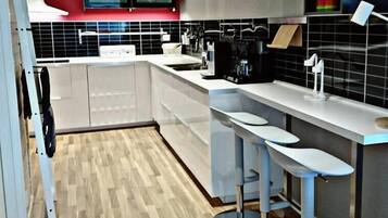 A modern kitchen with a central island, bar stools, and a red accent wall.