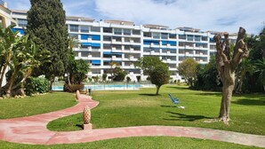 Un patio de hotel con piscina, palmeras y un sendero rojo.