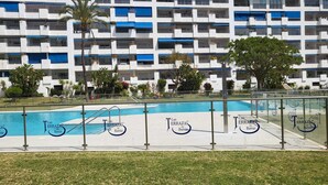 Un hotel moderno con varios balcones, una piscina y un césped bien cuidado.