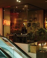 A modern interior with a glass partition, a DJ setup, and a neon sign.