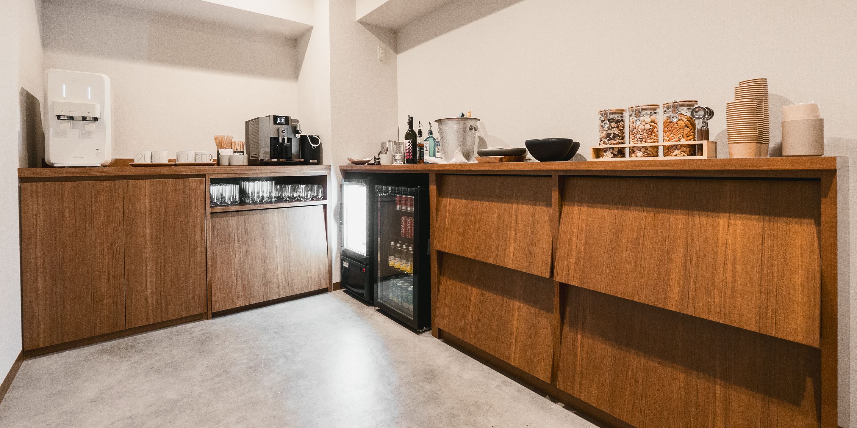 A compact kitchen with wooden cabinets, a coffee machine, a refrigerator, and various kitchen utensils.