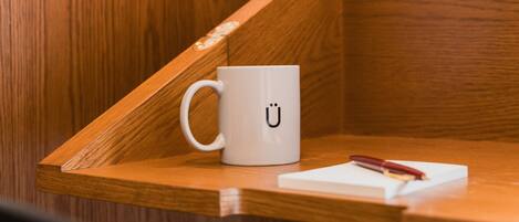A white mug with a black 'Ü' on a wooden surface.