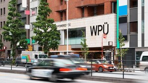 A multi-story building with a prominent 'WPÜ' sign, surrounded by trees and parked vehicles. - WPÜ HOTEL SHINJUKU (Tokyo)