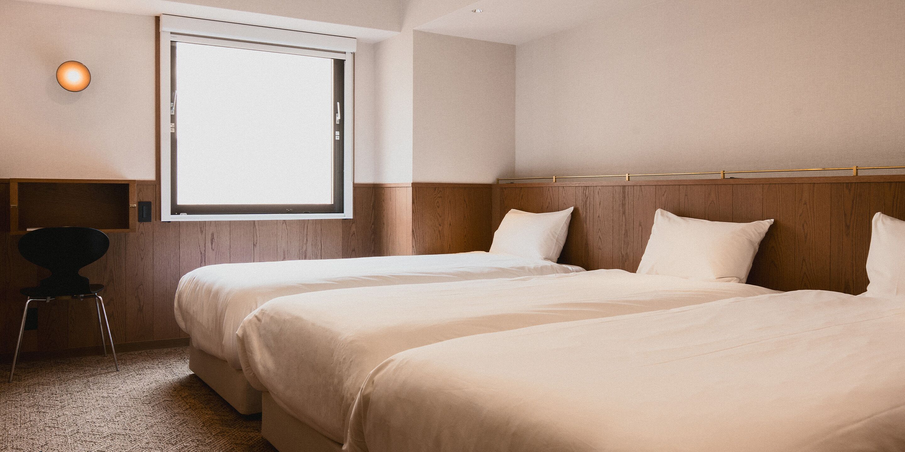 Habitación de hotel con dos camas, un escritorio y una ventana.