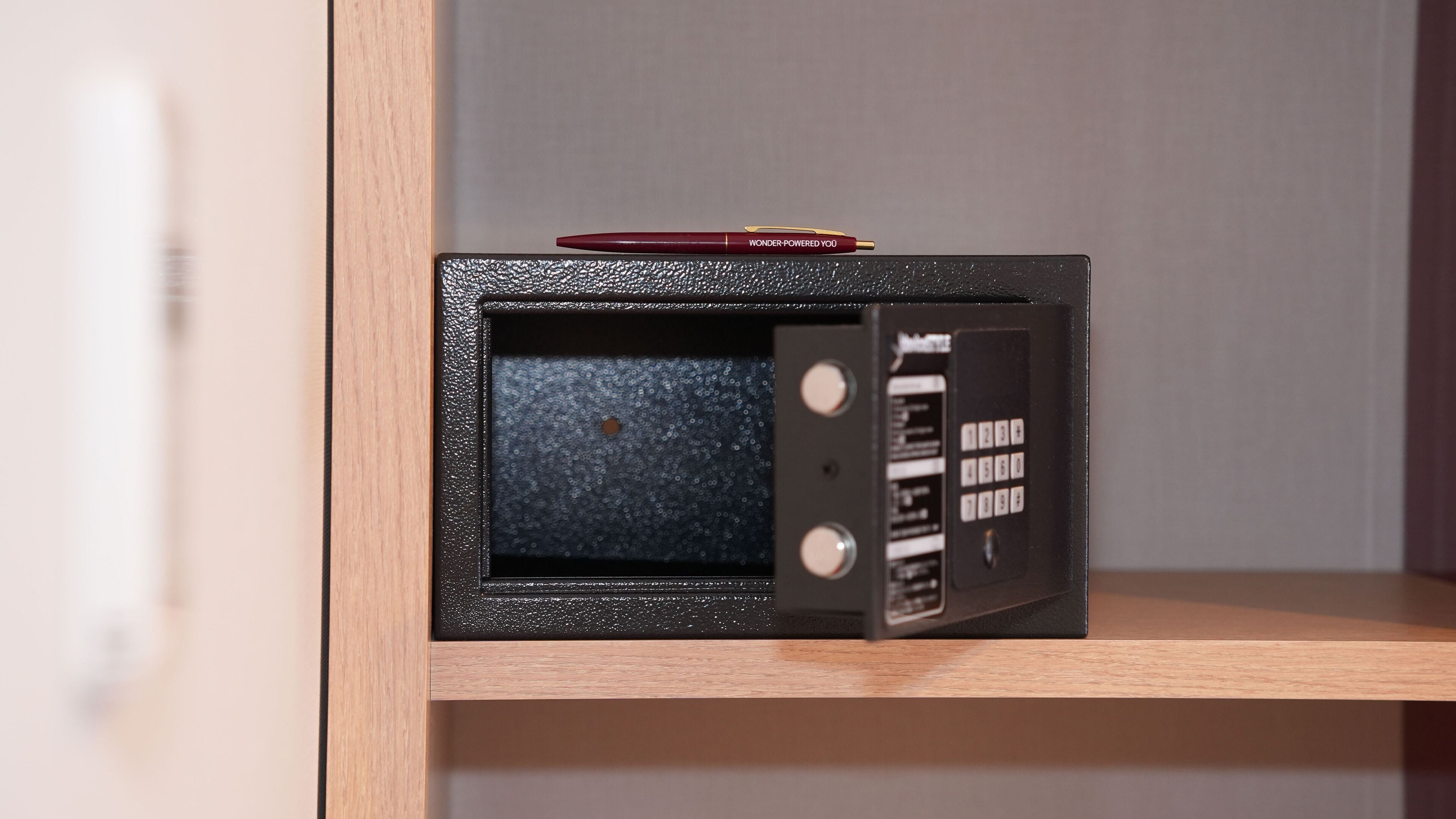 A black safe with a red pen on top, a keypad, and a small window.