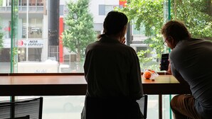 Two people sitting at a table by a window with a view of buildings and trees. - WPÜ HOTEL SHINJUKU (Tokyo)