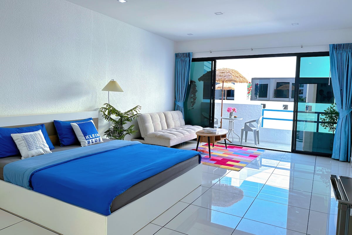 Ein modernes Hotelzimmer mit einem großen Bett, einer Couch, einem kleinen Tisch und einem Balkon mit Blick.
