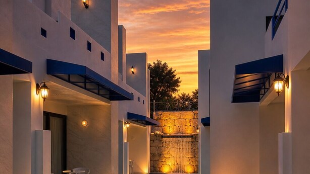 Un área de piscina moderna con una pared de piedra y vistas al atardecer.