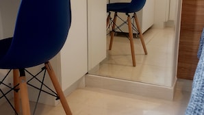Une pièce avec deux chaises bleues, un bureau et un miroir qui reflète la pièce.