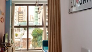 Un salon moderne avec une grande fenêtre, un panneau bleu sur le mur et une vue sur le paysage urbain.