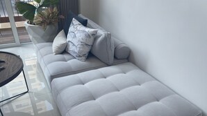 A modern living room with a light grey sofa, a round glass coffee table, and a potted plant. - Beach and Mountain View, pool.  (Puerto Vallarta)