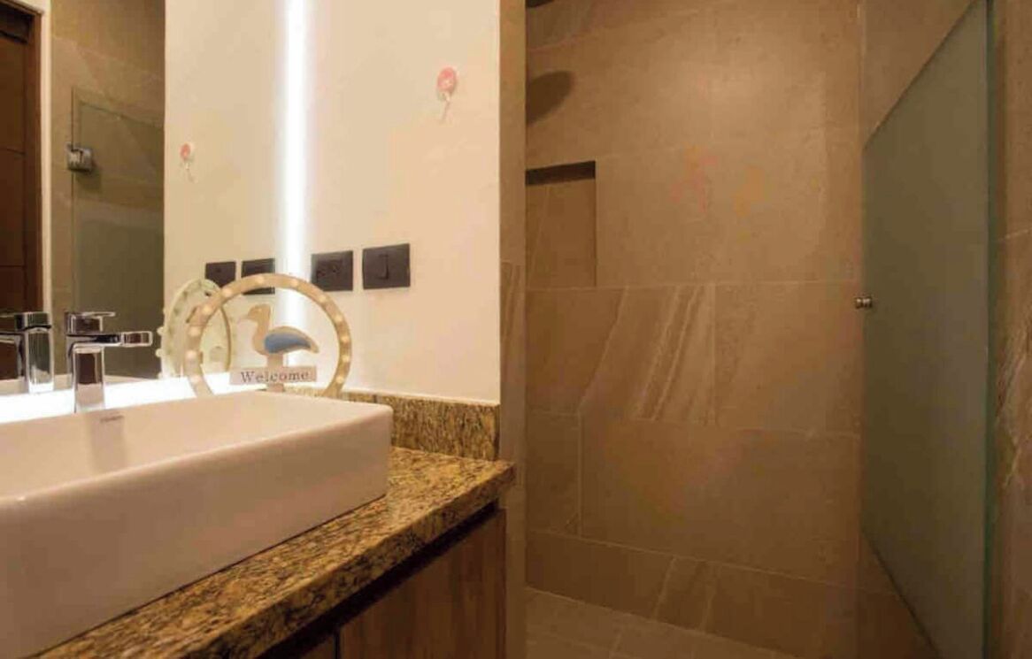 A bathroom with a large sink, a mirror, and a shower area.