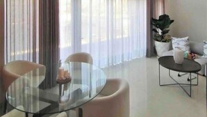 A modern living room with a glass dining table, two chairs, a sofa, and a large window with sheer curtains. - Beach and Mountain View, pool.  (Puerto Vallarta)