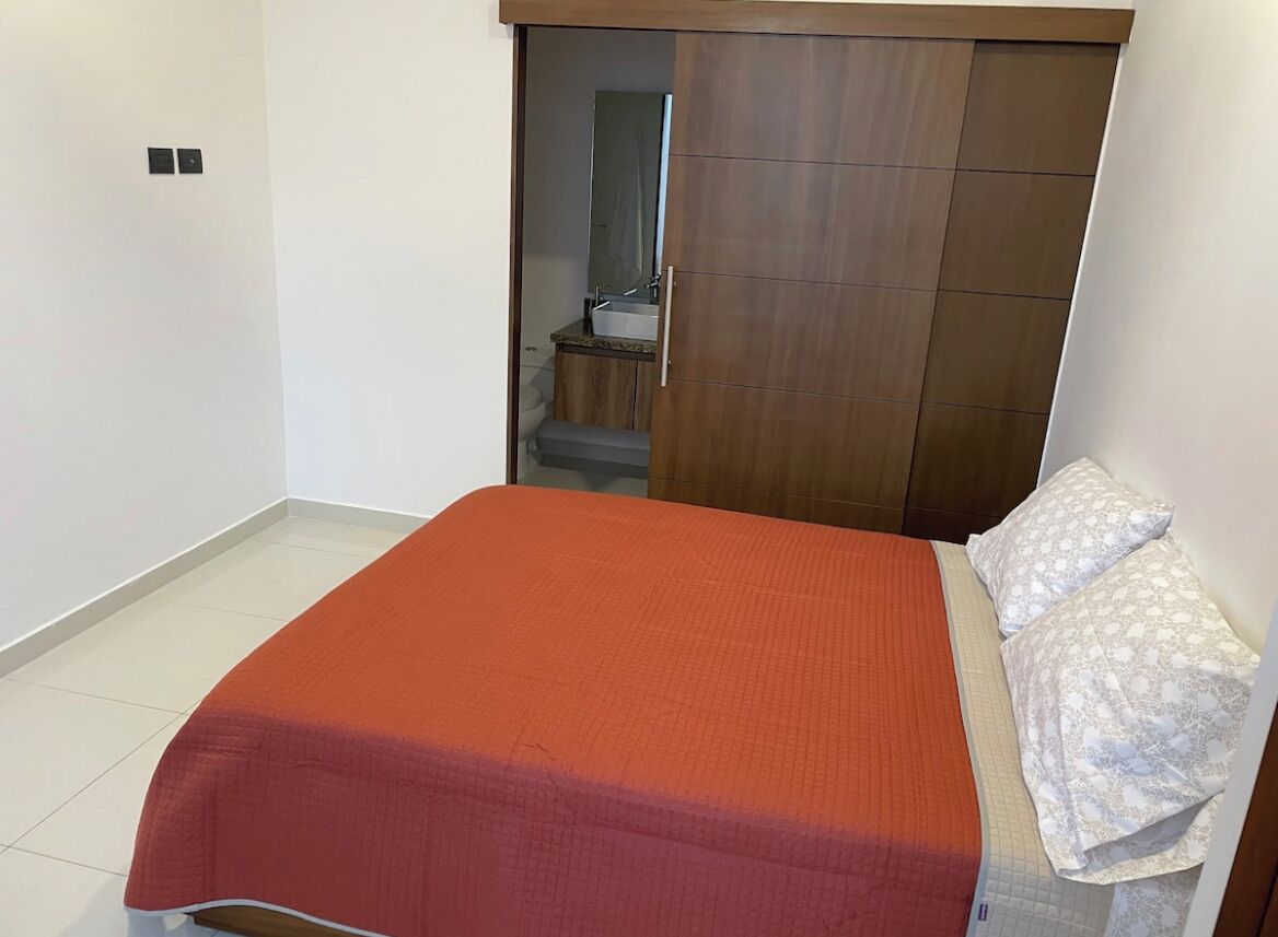 A bedroom with a bed, a wardrobe, and a bathroom visible through an open door.